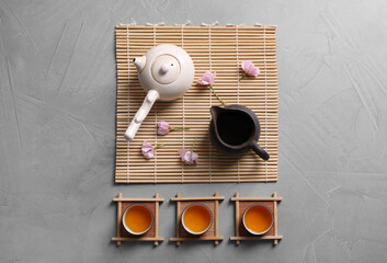 Beautiful set for traditional tea ceremony and sakura flowers on light grey table, flat lay