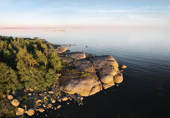 small island and man with boat, launching drone. Beautiful rocks and cliffs with woods in North Europe, Baltic sea, gulf of Finland.