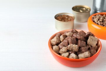 Wet pet food in feeding bowl on white wooden table. Space for text
