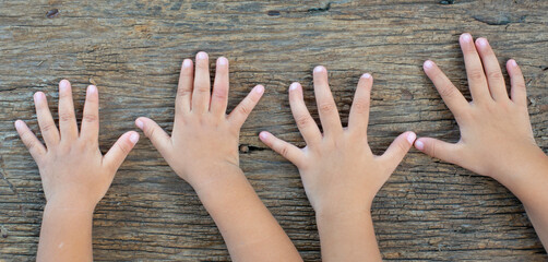 Many children hand playing on natural old wooden planks background.