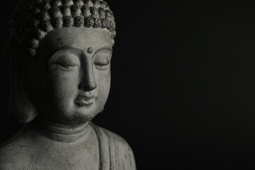 Beautiful stone Buddha sculpture on black background, closeup. Space for text