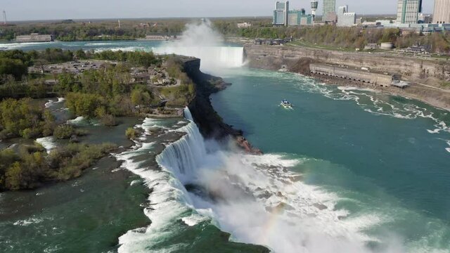 Flying above the edge of iconic Niagara Falls and small boat on Niagara River