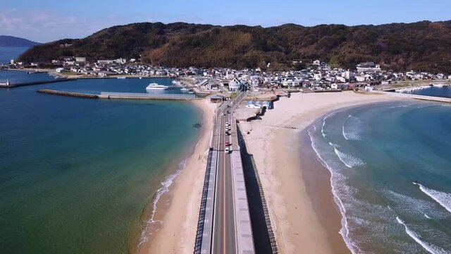 志賀島 青い海の中の砂州を走る道路上空を後ろに進む 空撮 トラックバック 日本