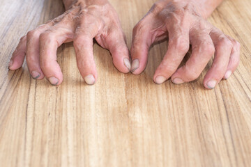 Old man's hands and fingers on wood texture background