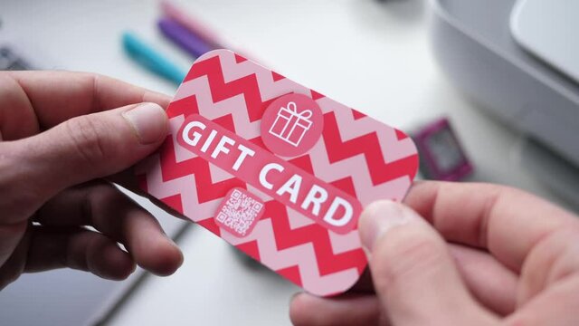 Holding a gift card with a QR code on it in the hands. Closeup shot