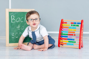 a baby with glasses and a blackboard that says soon to school is sitting with bills