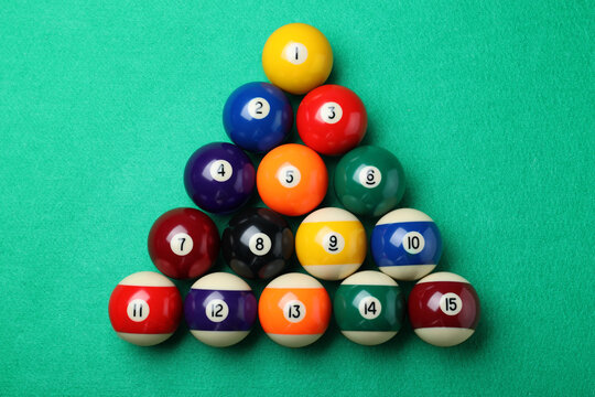 Set of billiard balls on green table, flat lay