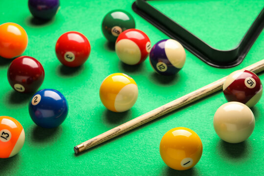 Many colorful billiard balls and cue on green table