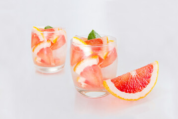 Grapefruit juice with grapefruit slice and ice in a glass on the table. Refreshing summer cocktail.