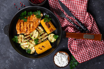 Grilled chicken breast with corn and zucchini on a pan top view. Summer dish with grilled chicken and vegetables.
