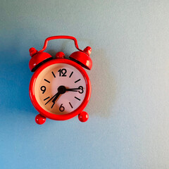 Red analog alarm clock on light background with copy space