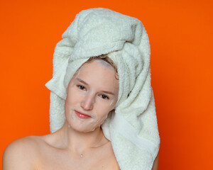 a girl with wet hair and a white towel on her head in a cosmetic mask with bare shoulders looks straight