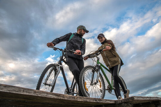 Couple - man and woman with bicycles on the background of the cloudy sky
