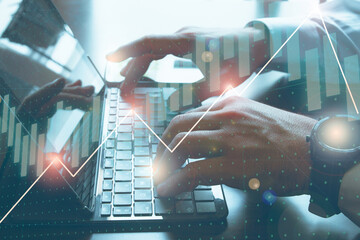Hands of a businessman typing in a computer with graphics overprinted. Stock exchange concept.