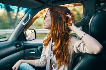 Naklejka premium happy red-haired woman in a beige coat in the front seat of a car smile model gesturing with her hands fellow traveler