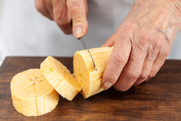 Closeup of a senior woman hands while cuts a ripe plantain