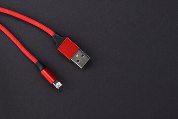 Detail of a red USB cable connector for a mobile phone on a black background.