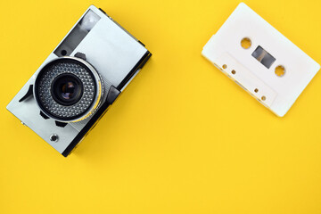 Old retro camera of the 1960s, 1970s in silver color on a yellow background. Audio cassette