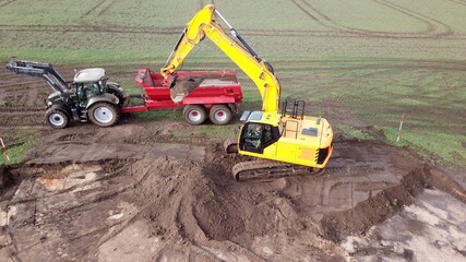 Baustelle: Tiefbau Erdbau Bauarbeiten: Bagger verlädt Erde, Sand auf einen Muldenkipper,...
