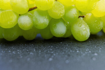 Closeup view of grapes lying on a dark slate desk. Horizontally.