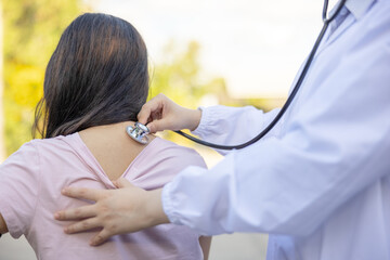 Doctor examines an women patient with a stethoscope in a summer park.