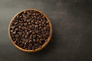 Coffee beans in wooden bowl on grunge background.