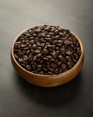 Coffee beans in wooden bowl on grunge background.