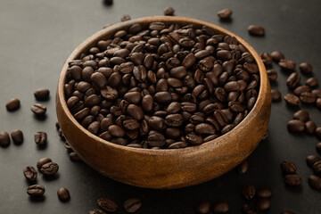 Coffee beans in wooden bowl on grunge background.