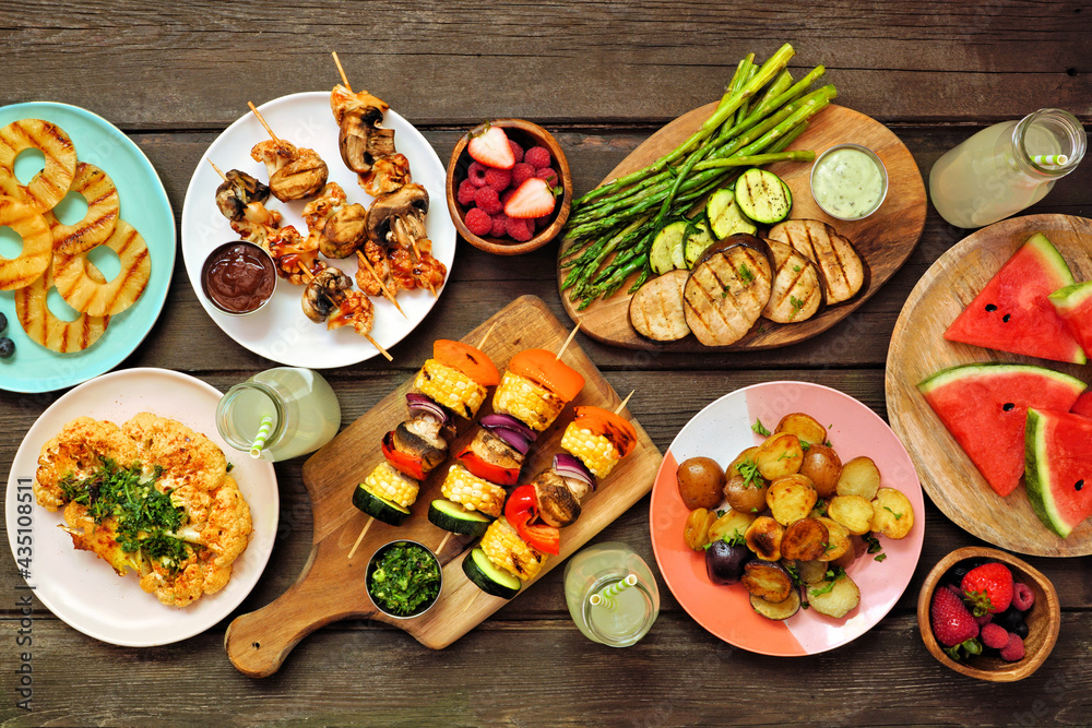 Canvas Prints Vegan summer bbq or picnic table scene. Top view over a dark wood background. Grilled fruit and vegetables, skewers, cauliflower steak and vegetarian sides. Meat substitute concept.