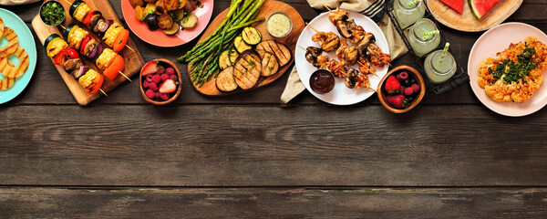 Healthy plant based summer bbq top border. Above view over a dark wood banner background. Grilled...