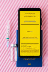 Vaccine bottle, syringe and vaccination passport on a pink background. Yellow international...