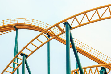 minimalist shot of yellow roller coaster tracks against the white sky