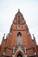 Fototapeta na wymiar Gothic catholic cathedral of red brick and pointed spiers. Bottom view. Greatness and beauty (843)