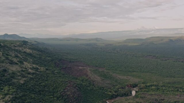 Aerial view of the Omo Valley in Ethiopia. Landscape of savannah overgrown with trees and surrounded by mountains, peaks and ridges. Drone video of Africa and the place from which humanity was born.