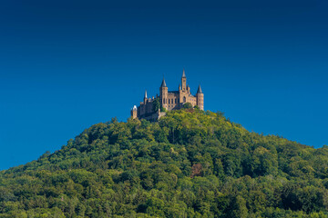 Obraz premium Aerial view of famous Hohenzollern Castle, ancestral seat of the imperial House of Hohenzollern and one of Europe's most visited castles, on the top of a green hill in Baden-Wurttemberg, Germany