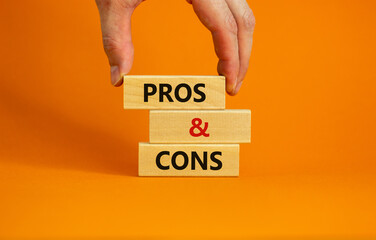 Pros and cons symbol. Wooden blocks with words 'Pros and cons'. Beautiful orange background, businessman hand. Business, pros and cons concept, copy space. - obrazy, fototapety, plakaty