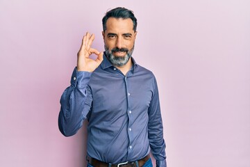 Obraz premium Middle age man with beard and grey hair wearing business clothes smiling positive doing ok sign with hand and fingers. successful expression.