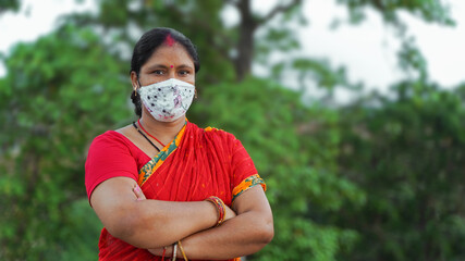 Beautiful smiling Indian woman in a protective face mask, isolated over outdoor background