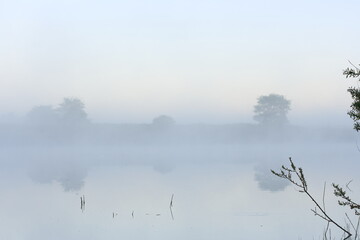 Obraz na płótnie Canvas Dense morning fog over the river in late spring