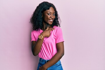 Beautiful african young woman wearing casual pink t shirt smiling cheerful pointing with hand and finger up to the side