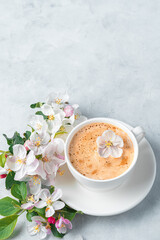A white cappuccino cup and beautiful flowers on a light gray background.