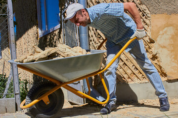 removal of construction debris by wheelbarrow,man pushes a full wheelbarrow of construction debris