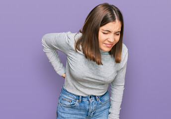 Young beautiful woman wearing casual turtleneck sweater suffering of backache, touching back with hand, muscular pain
