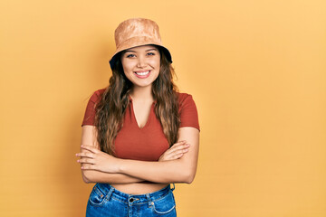 Young hispanic girl wearing casual clothes and hat happy face smiling with crossed arms looking at the camera. positive person.