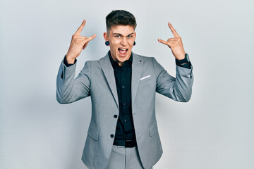 Young caucasian boy with ears dilation wearing business jacket shouting with crazy expression doing rock symbol with hands up. music star. heavy music concept.