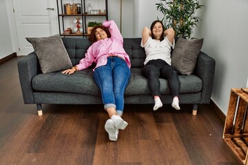Fototapeta premium Mature mother and down syndrome daughter at home resting on the sofa