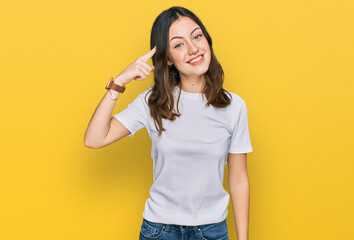 Young beautiful woman wearing casual white t shirt smiling pointing to head with one finger, great idea or thought, good memory