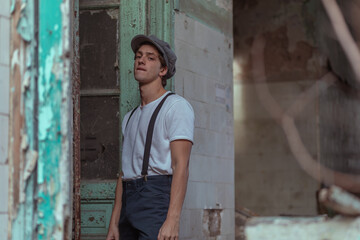 Joven en construcción abandonada vestido con gorro tiradores y camiseta