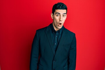 Handsome hispanic man wearing business clothes afraid and shocked with surprise expression, fear and excited face.