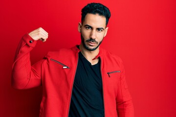 Young hispanic man wearing red leather jacket strong person showing arm muscle, confident and proud of power